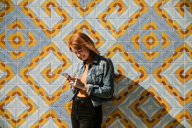 Donna che usa il telefono su un muro moderno