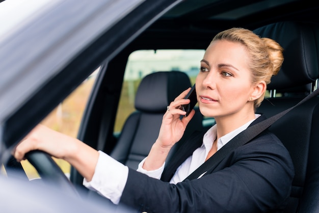 女性は車を運転している間彼女の電話を使用して