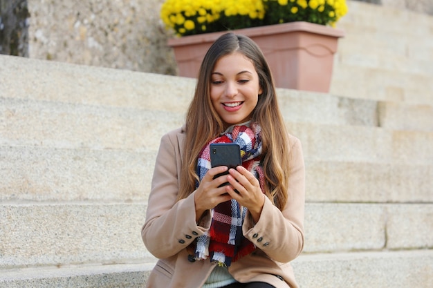 Woman using her phone while walking in the city