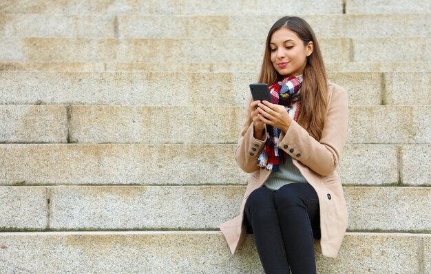 Woman using her phone while walking in the city