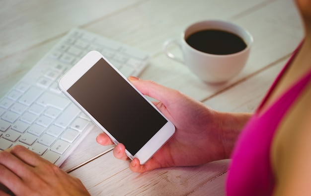 Woman using her smartphone and keyboard