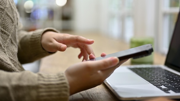 A woman using her smartphone while working on her tasks at her desk