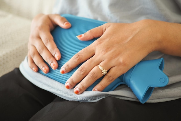 Woman using hot water bag for period pain