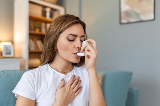 Photo woman using inhaler while suffering from asthma at home young woman using asthma inhaler closeup of a young woman using asthma inhaler at home