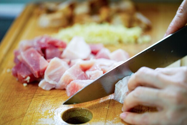 Photo woman using a knife to cut pork for prepare for lunch