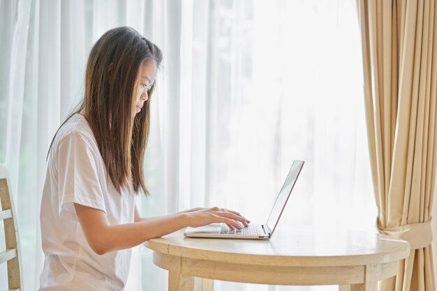 Woman using laptop for the application on table in room.