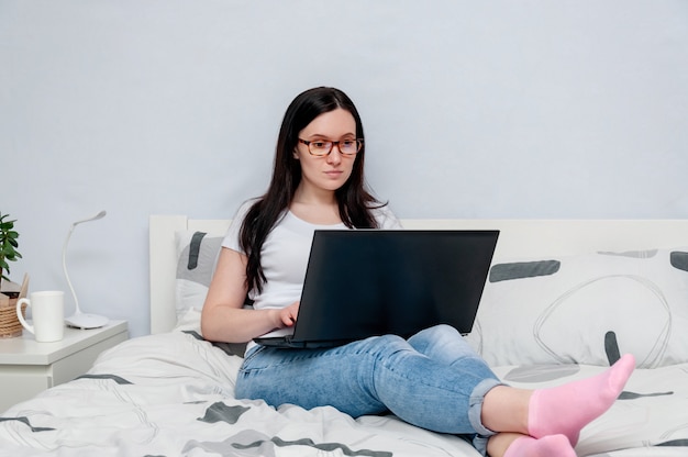 Женщина, используя портативный компьютер на кровати у себя дома