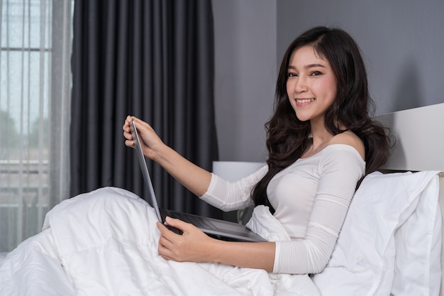 Женщина, используя портативный компьютер на кровати