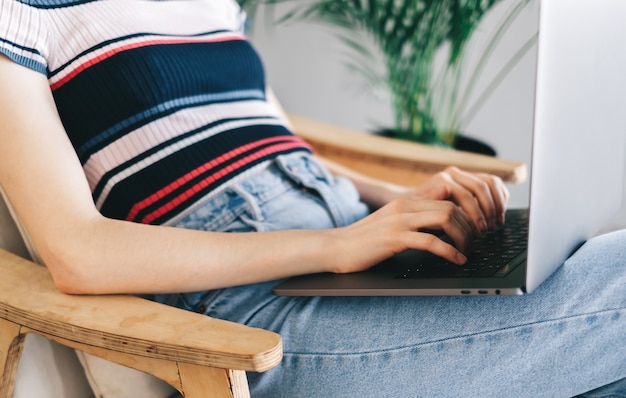 Woman using laptop computer and typing on keyboard. Freelancer working distantly at home.