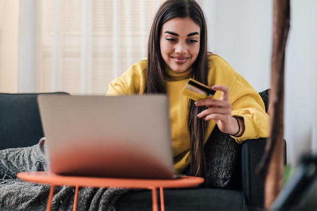 Woman using laptop from sofa working from home in quarantine lockdown social distancing female at home shopping online happy young person working surfing web paying app computer at home living room