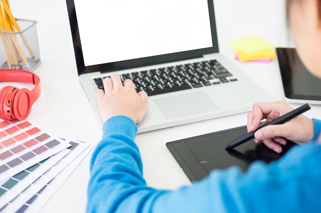 Woman using laptop and graphics tablet at creative office
