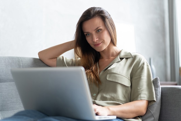 Donna che utilizza un computer portatile nel suo soggiorno. lavorare da casa in quarantena. riduzione dei contatti.