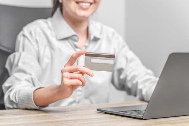 Woman using laptop and holding credit card in hands.