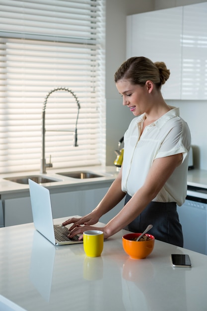 Donna che utilizza computer portatile nella cucina