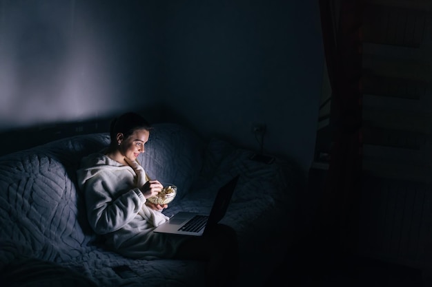 Woman using laptop at night at home in the living room watch mo