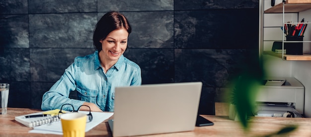 Donna che utilizza computer portatile nell'ufficio e nel sorridere