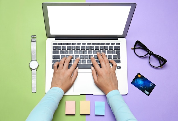 Woman using laptop for online shopping on color wall