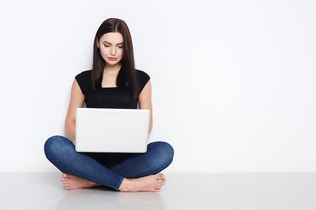 Woman using laptop sitting on the studio floor