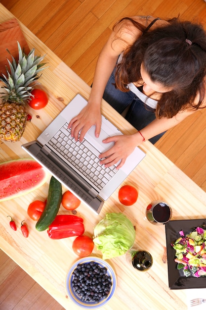 Woman using a laptop while cooking