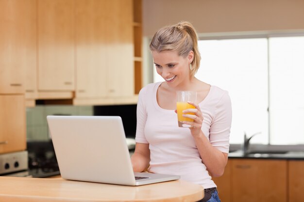 Photo woman using a laptop while drinking juice