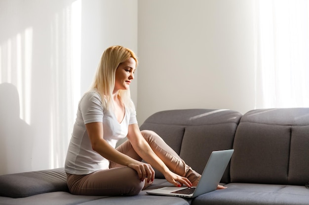 Woman using a laptop while relaxing on the couch