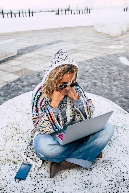 Фото Женщина использует ноутбук, сидя на улице
