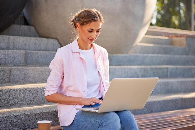 Photo woman using laptop while sitting on staircase