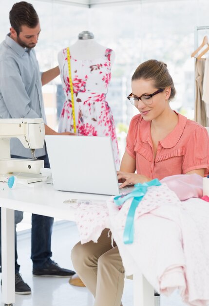 Foto donna che utilizza computer portatile con lo stilista che lavora in studio