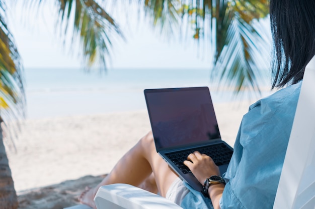 woman using laptop to work and study in vacation day at beach.