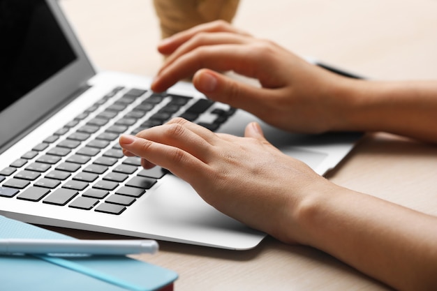 Woman using laptop on workplace close up