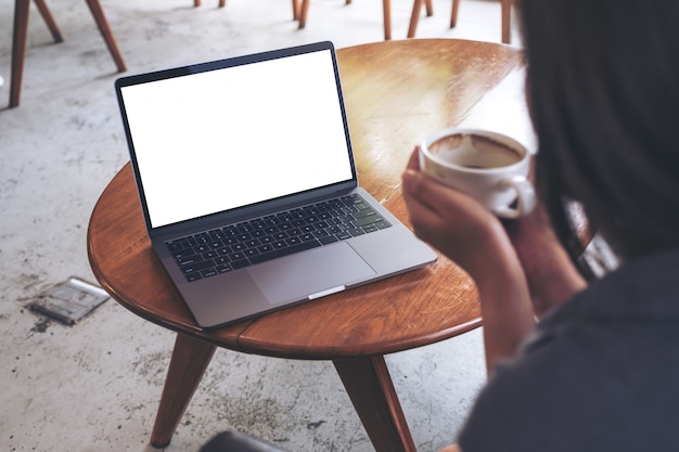 Woman using and looking at laptop with blank white desktop screen