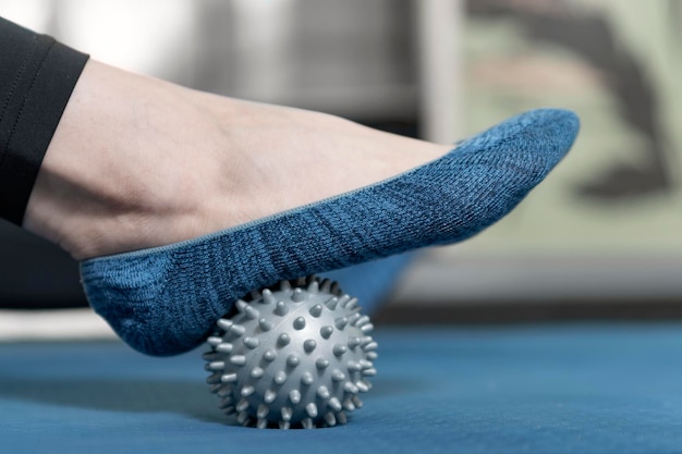 Woman using massage tool for myofascial therapy on foot. Close up. Ball for Myofascial massage. MFR.