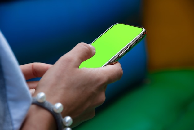 クロマキーの緑色の画面でスマートフォンでモバイルアプリを使用している女性