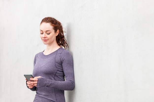 Photo woman using mobile phone after training session