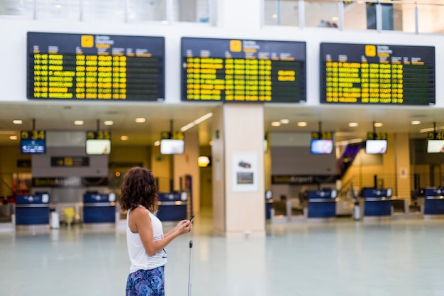 Foto donna che usa il cellulare all'aeroporto