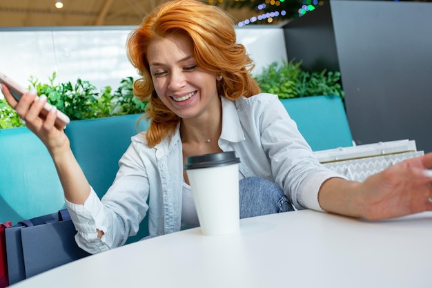 ショッピングモールのカフェで携帯電話を使用している女性