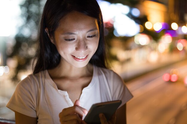 Woman using mobile phone in the city at night