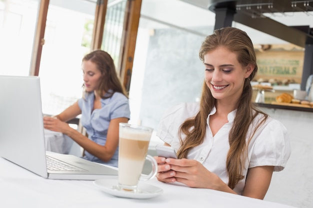 コーヒーショップで携帯電話を使っている女性