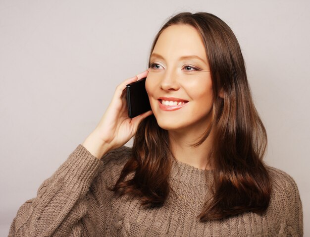 Donna che per mezzo di un telefono mobile isolato su un bianco