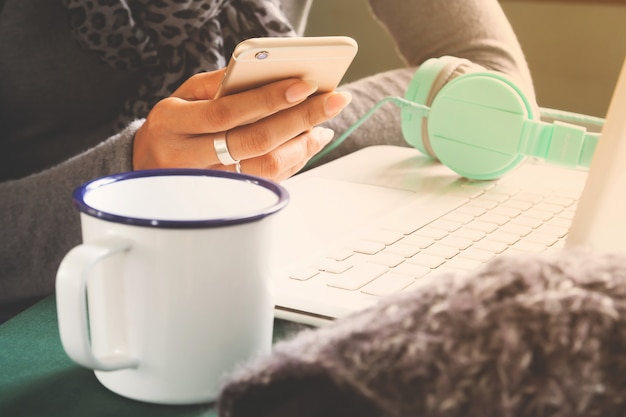 Woman using mobile phone and laptop on workspace desk. Technology lifestyle concept