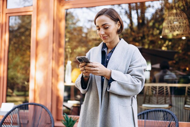 Photo woman using mobile phone outside coffee shop