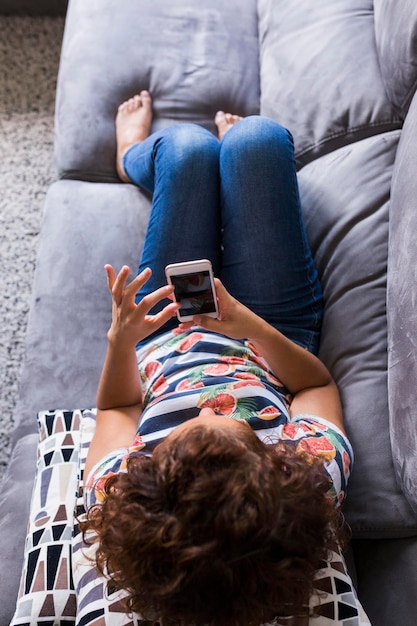 自宅のソファで携帯電話を使っている女性