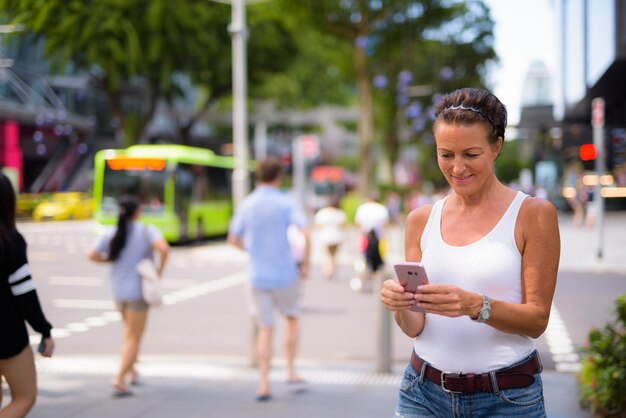 Woman using mobile phone on street in city