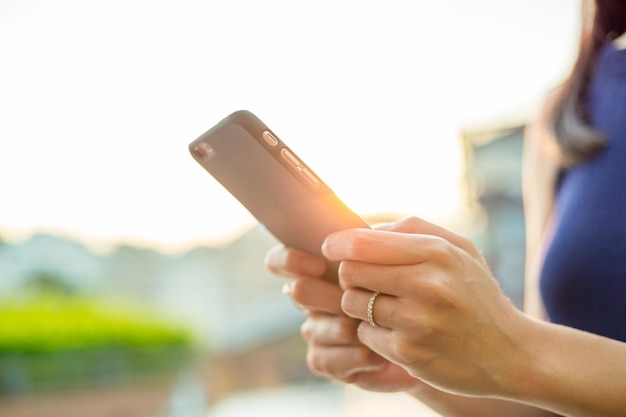 Foto donna che utilizza il telefono cellulare sotto il chiarore del sole