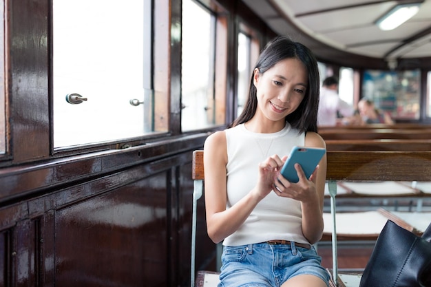 Woman using mobile phone and taking ferry in Hong Kong