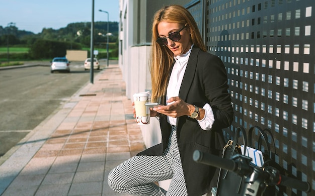 woman using mobile phone while leaning on wall