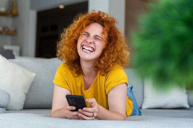 Woman using mobile phone while lying on sofa Young female is resting at home