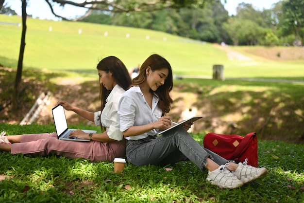 Photo woman using mobile phone while sitting on grass