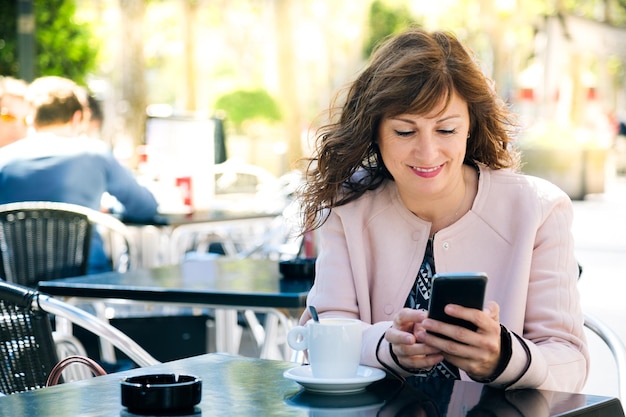 woman using mobile phone while sitting on table