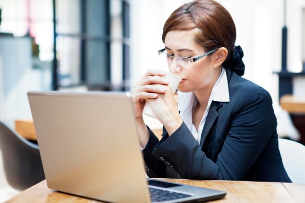 Photo woman using mobile phone while sitting on table